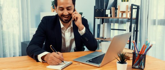 Dirigeant de TPE échangeant en visioconférence avec son assistant virtuel depuis son bureau.