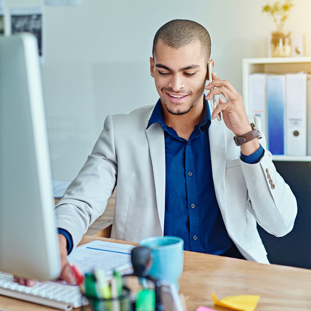 Commercial échangeant au téléphone avec un prospect depuis un bureau équipé d’un casque et d’un ordinateur.