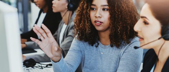 Formateur animant une session de formation au télémarketing devant des conseillers équipés de casques.