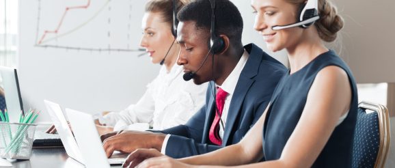 Téléprospecteur en formation échangeant avec un client au téléphone, avec des notes de qualification devant lui.