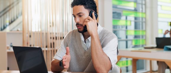 Personne s’exerçant à la téléprospection devant un ordinateur et un téléphone