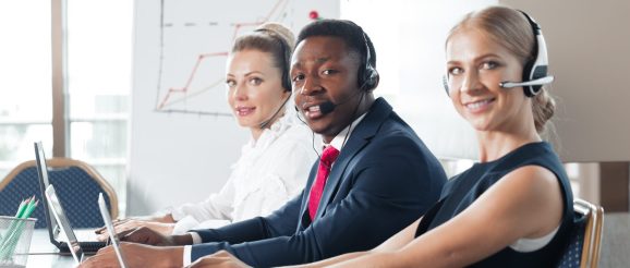 Un formateur accompagne une nouvelle commerciale pendant un appel de téléprospection au bureau.