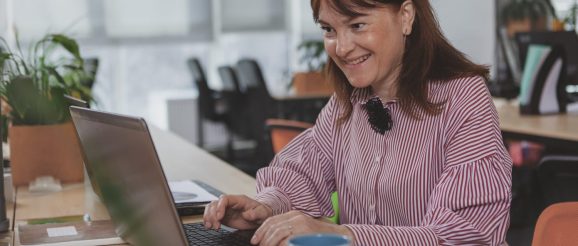 Assistante digitale freelance travaillant sur son ordinateur portable avec un carnet de budget.