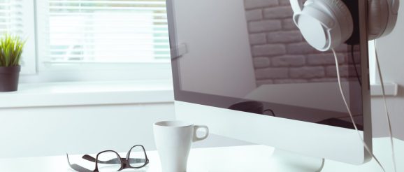 Une personne travaille sur un ordinateur portable depuis un bureau organisé, avec un agenda et un carnet pour gérer ses tâches d’assistant virtuel.