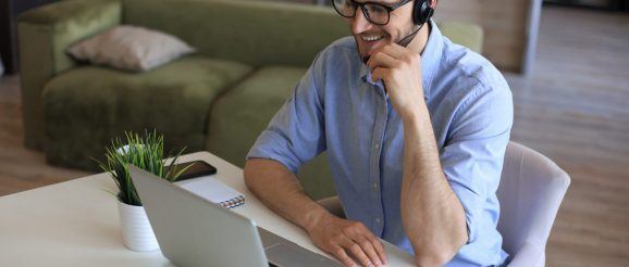 Téléprospectrice travaillant depuis son domicile, casque sur les oreilles, en train de passer un appel commercial depuis son bureau.