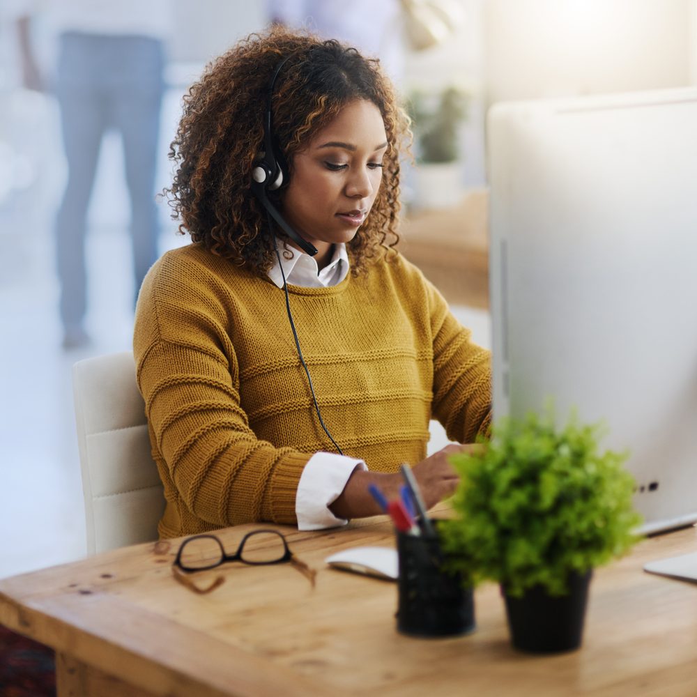 Consultant indépendant en téléprospection passant un appel depuis un espace de travail organisé, casque audio et tableau de prospects à portée de main.