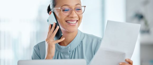 Téléopérateur consultant son bulletin de salaire à côté d’un téléphone et d’un ordinateur.
